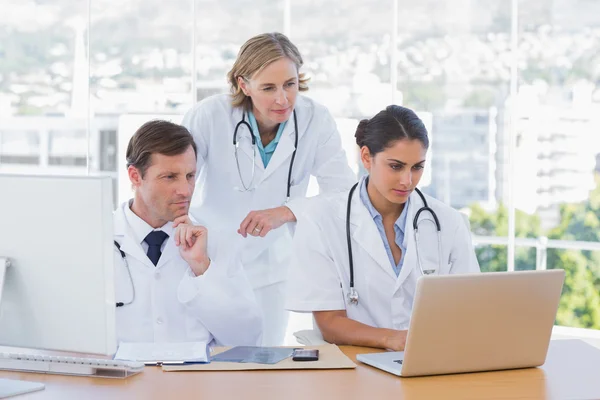 Equipe médica trabalhando em conjunto em um laptop e um computador — Fotografia de Stock