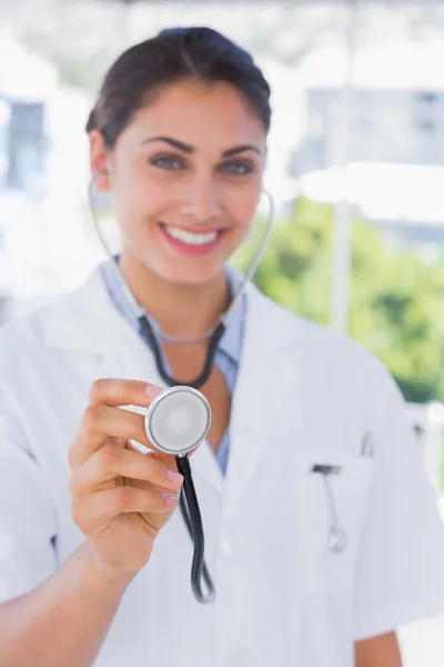 Glad ung läkare håller upp stetoskop — Stockfoto