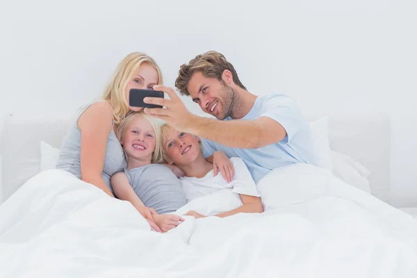 Cheerful family taking self pictures with a smartphone — Stock Photo, Image