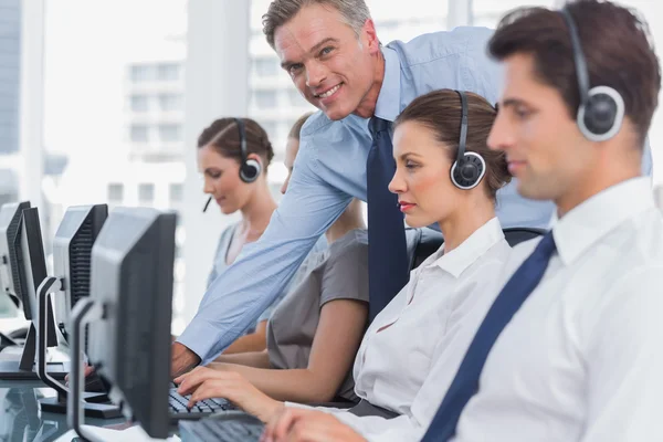 Smiling manager helping call centre employee — Stock Photo, Image