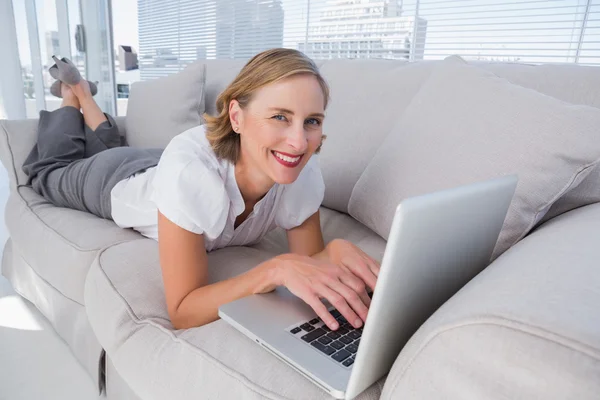 Donna d'affari sdraiata sul divano utilizzando il suo computer portatile — Foto Stock