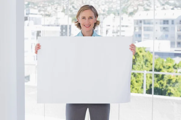 Happy businesswoman holding large white poster — Stock Photo, Image