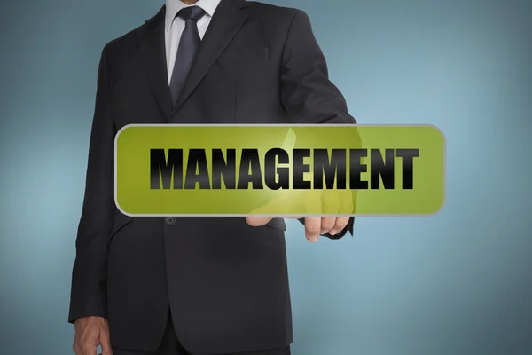 Бизнесмен трогает слово "менеджмент", написанное на зеленой бирке — стоковое фото