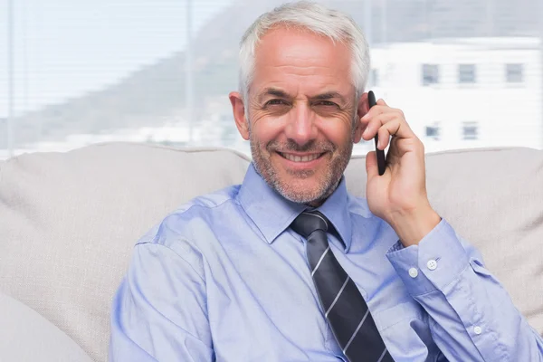 Бизнесмен звонит на смартфон и улыбается в камеру — стоковое фото