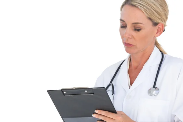 Doctor with stethoscope around her neck writing on clipboard — Stock Photo, Image