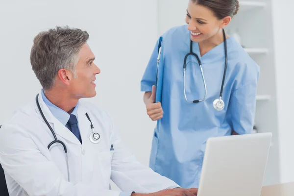 Doutor com uma prancheta conversando com um colega — Fotografia de Stock