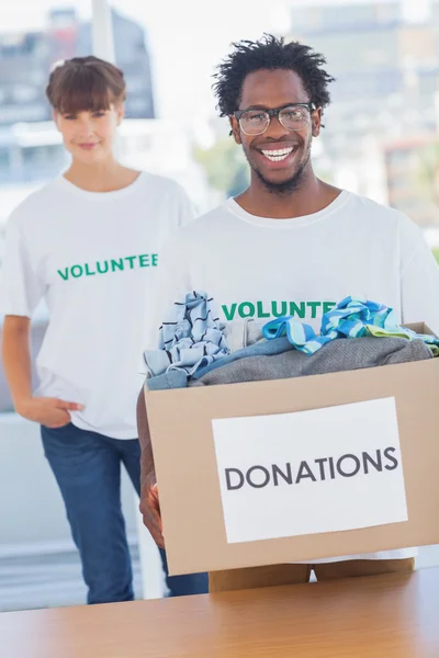 Hombre guapo sosteniendo caja de donaciones junto a un colega — Foto de Stock