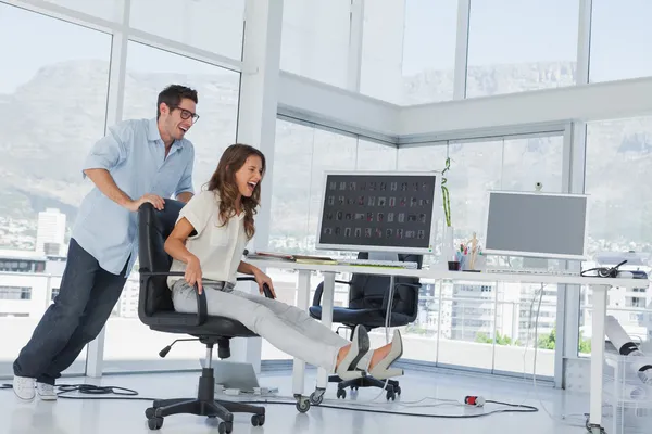 Diseñadores divirtiéndose con una silla giratoria — Foto de Stock