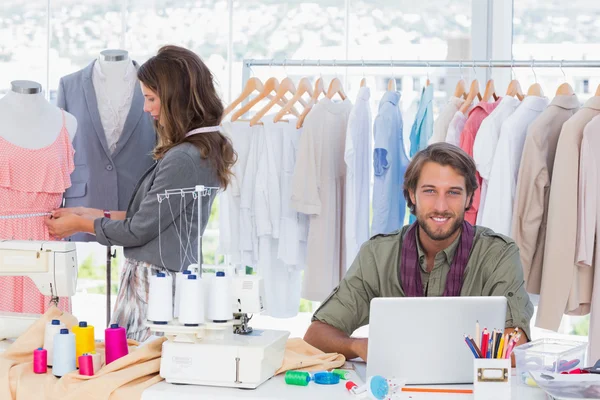 Diseñador de moda usando el ordenador portátil y sonriendo a la cámara — Foto de Stock