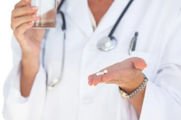 Médico sosteniendo tabletas y vaso de agua — Foto de Stock