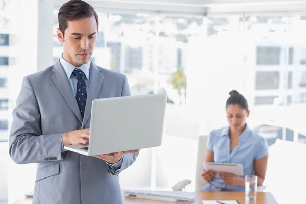 Бизнесмен с помощью ноутбука, стоящего в офисе — стоковое фото