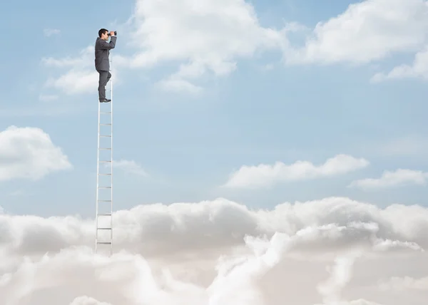 Zakenman permanent op een ladder boven de wolken — Stockfoto