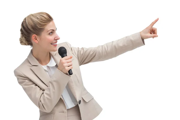 Businesswoman with microphone indicating something — Stock Photo, Image