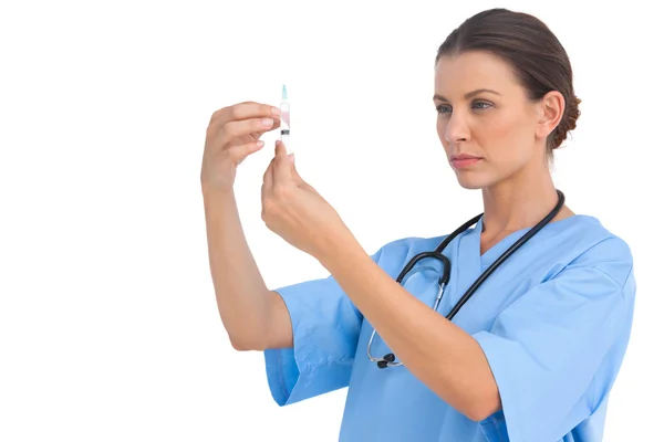 Serious surgeon holding up needle and checking it — Stock Photo, Image