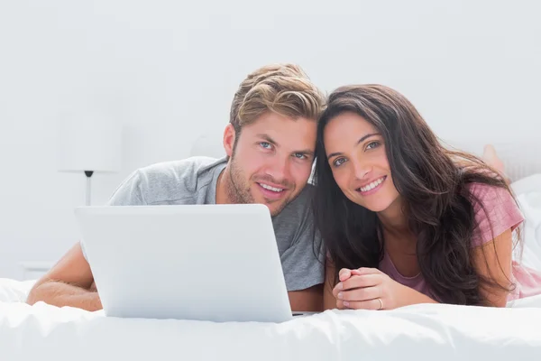 Pareja alegre con portátil en la cama —  Fotos de Stock