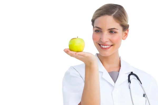 Enfermera mirando la manzana colocada en su mano — Foto de Stock