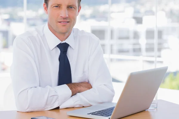 Geschäftsmann mit verschränkten Armen auf seinem Schreibtisch — Stockfoto