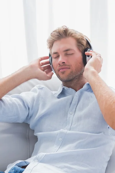 Homem relaxante enquanto ouve música em um sofá — Fotografia de Stock