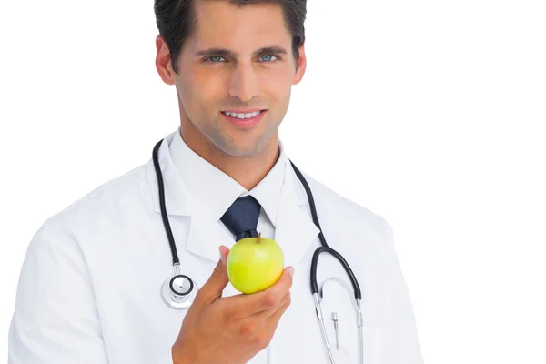 Läkaren håller ett äpple och ler — Stockfoto