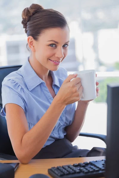 Femme d'affaires tenant une tasse de café et souriant — Photo