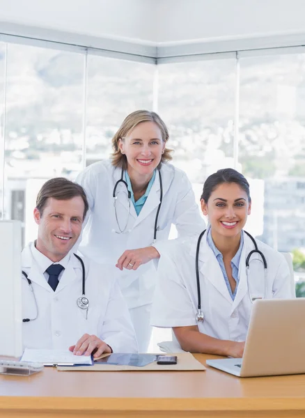 Equipe médica sorrindo trabalhando em um laptop e um computador — Fotografia de Stock