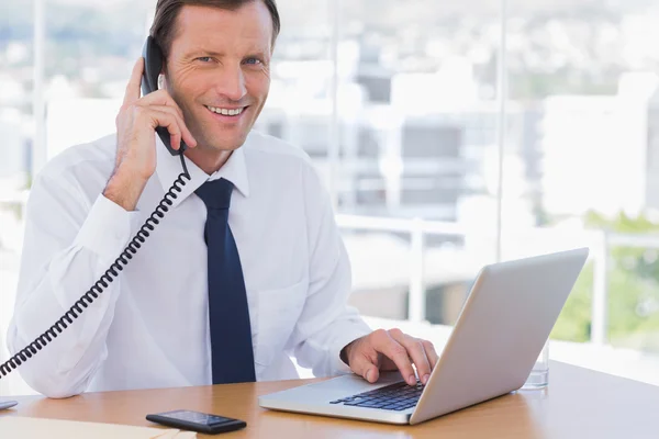 Улыбающийся бизнесмен позирует, пока разговаривает по телефону — стоковое фото