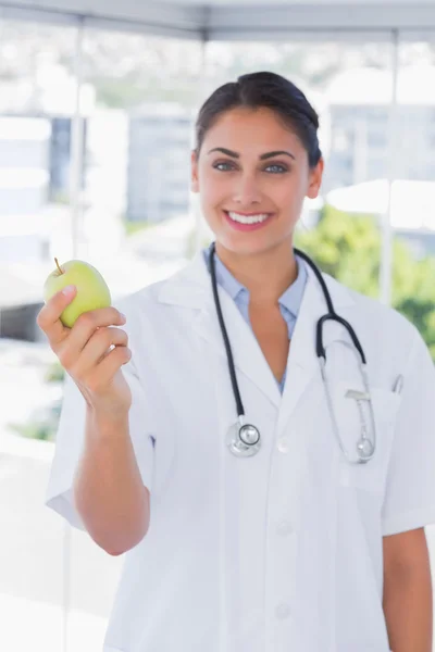 Pretty young doctor holding a green apple — Stock Photo, Image