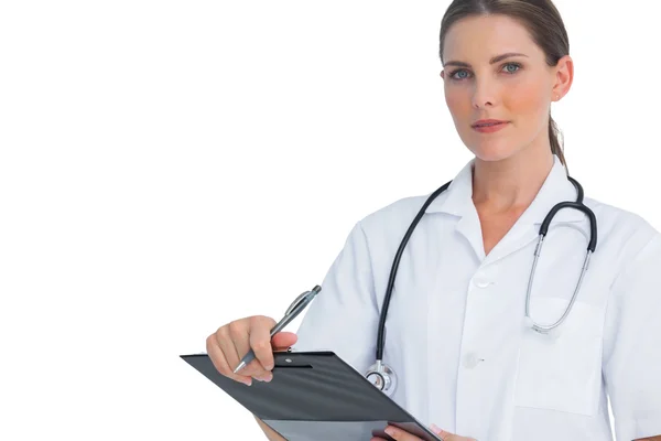 Unsmiling nurse holding clipboard and looking at camera — Stock Photo, Image