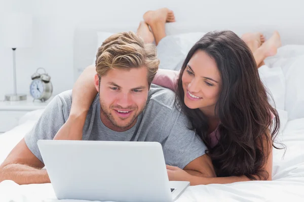 Mulher atraente abraçando o marido enquanto usa um laptop — Fotografia de Stock