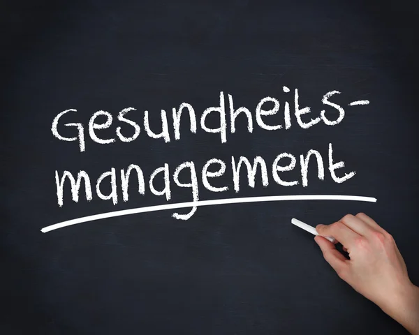 Рука пишет немецкие слова gesundheits управления — стоковое фото