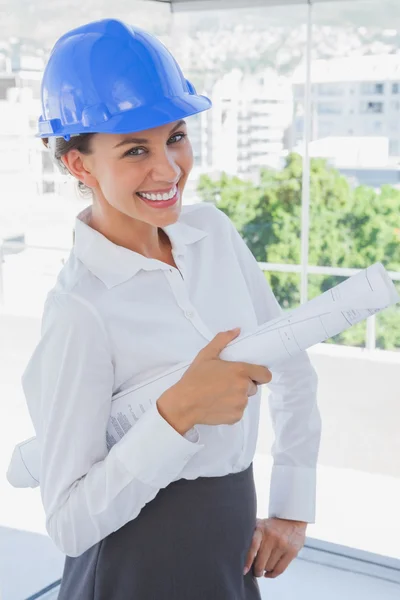 Smiling architect holding plans and wearing hardhat — Stock Photo, Image