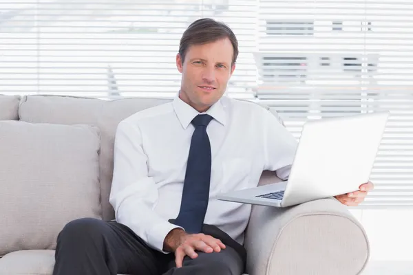 Geschäftsmann sitzt auf Couch und blickt in Kamera — Stockfoto