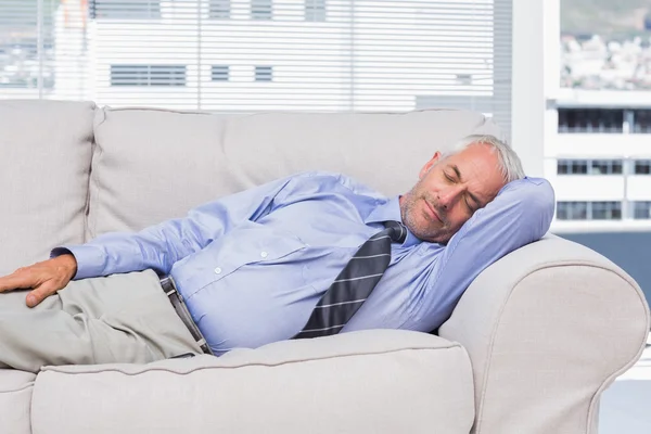 Businessman lying on sofa asleep — Stock Photo, Image