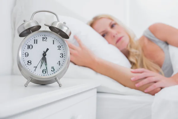 Tired woman looking at the alarm clock — Stock Photo, Image