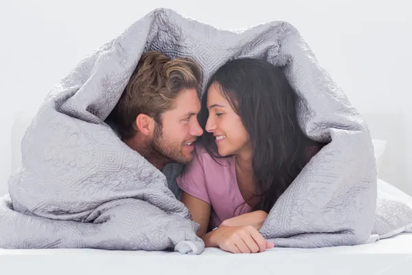 Attractive couple wrapped in the duvet — Stock Photo, Image