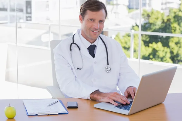 Médico sorridente trabalhando em um laptop — Fotografia de Stock