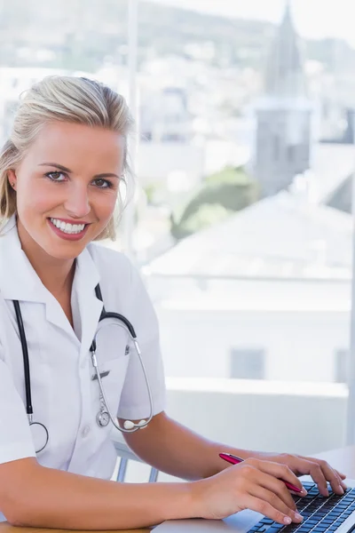 Lachende verpleegster die op haar laptop werkt — Stockfoto