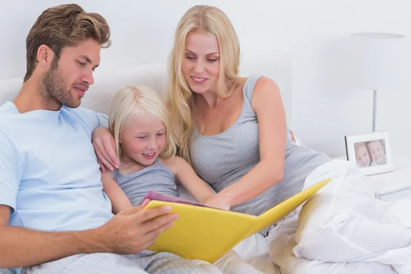 Beautiful couple reading a story to daughter — Stock Photo, Image