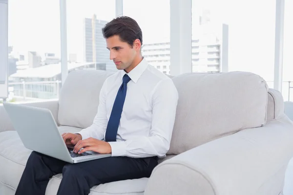 Businessman using laptop on a couch — Stock Photo, Image