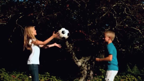 Vrolijke broers en zussen plezier met een voetbal op een trampoline — Stockvideo