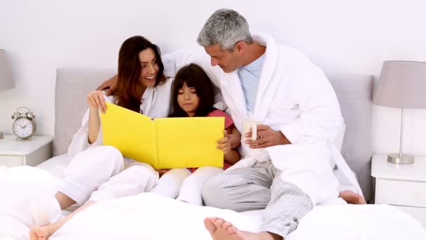 Родители и их дочь читают книги — стоковое видео