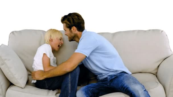 Father tickling his son on the sofa on white background — Stock Video