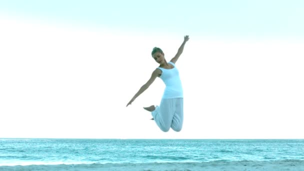 Привлекательная женщина прыгает по пляжу — стоковое видео