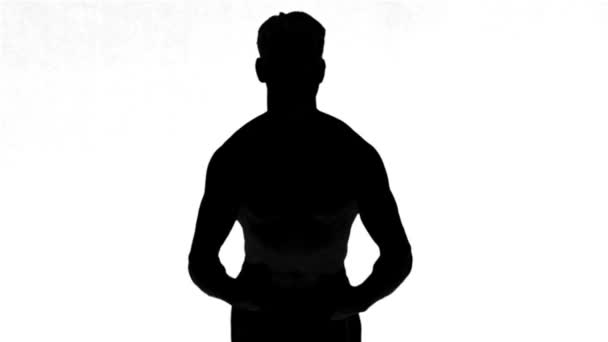 Silhouette di un uomo che tende i muscoli su sfondo bianco — Video Stock