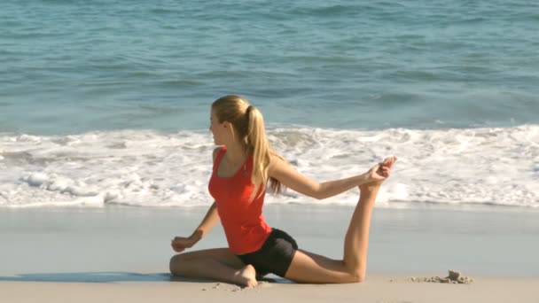 Donna che allunga la gamba sulla spiaggia — Video Stock