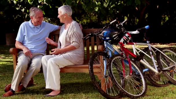 Зрелая пара разговаривает в парке рядом с горными велосипедами — стоковое видео