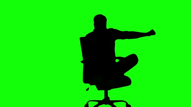Силует людини, що повертає поворотне крісло на зеленому екрані — стокове відео