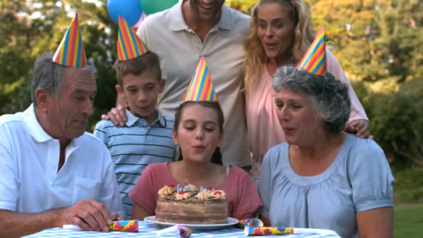 Счастливая семья задувает свечи праздничного торта — стоковое видео