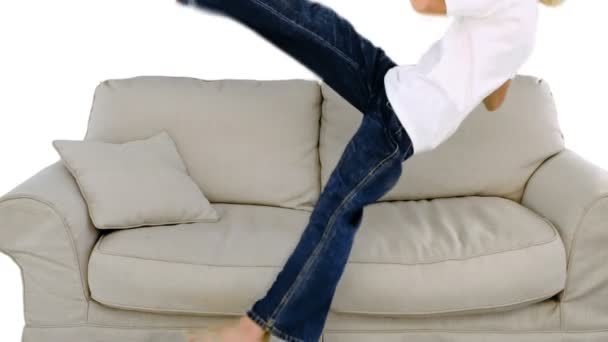 Ung pojke hoppar i soffan på vit bakgrund — Stockvideo