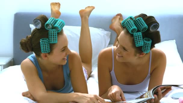 Vänner med hår roller skrattar medan du läser en tabloid — Stockvideo